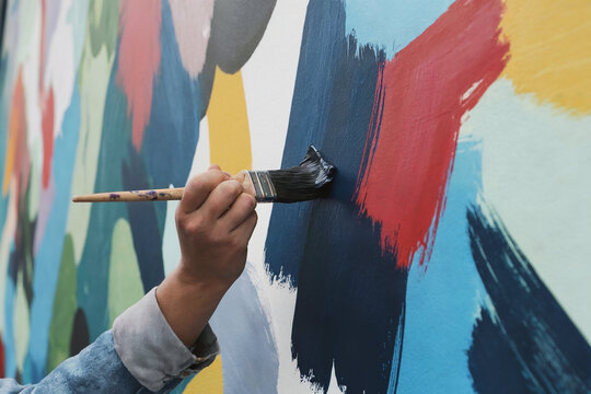 Artist applying vibrant paint to a mural - Powered by Adobe