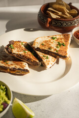 Vegan black bean quesadillas with guacamole, salsa, and chips on white