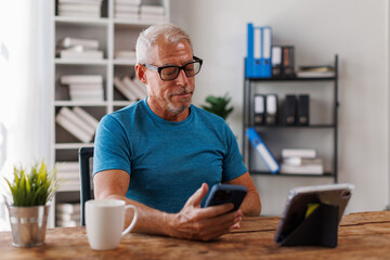 Senior, man having remote online work hybrid meeting or distance job interview, holding cup of coffee, gesturing with hands during virtual video conference call from home.