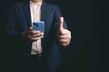 Confident man showing thumbs up with smartphone in hand