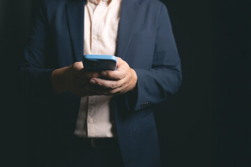 man in suit using smartphone in dark setting