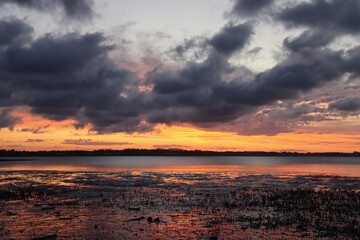 Dramatic sunset over a calm bay with a vibrant orange and purple sky