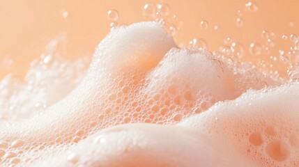Fototapeta premium Close up with soap foam and bubbles made of shampoo, lotion, detergent. Macro photo of spume on peach background. Banner with copy space for laundry, cleaning services, beauty, skin care concept 