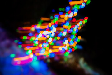 A mesmerizing array of colorful lights twinkles and swirls through the night, illuminating the dark surroundings and evoking a joyful festive spirit within the park square. 