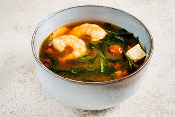 A hearty bowl of shrimp and tofu soup showcases succulent shrimp swimming alongside fresh greens and tender vegetables. Perfect for a cozy dining experience. 