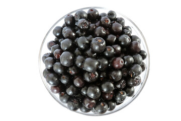 Fresh aronia berries in a glass bowl, white background, top view