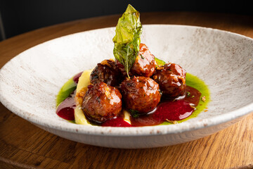 Delight in a plate of perfectly cooked swedish meatballs, glistening with a luscious sauce, nestled beside creamy mashed potatoes and vibrant green garnish. Ideal for a comforting meal. 