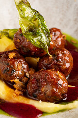 Savor the mouthwatering taste of Swedish meatballs nestled on a bed of velvety mashed potatoes, drizzled with a luscious sauce, garnished with a crispy leaf for added crunch. 