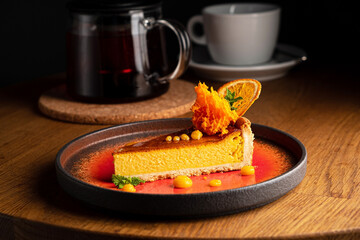 Savor the rich flavors of a pumpkin cheesecake adorned with orange zest and fresh carrot shavings,...