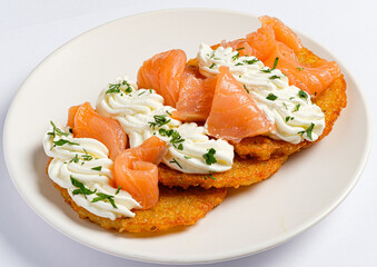 Golden potato pancakes serve as a base for generous dollops of creamy cheese, elegantly topped with silky smoked salmon and fresh herbs. 