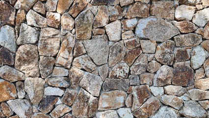 rock wall. Natural stone wall used as background or texture. Stone wall structure. Seaside stone wall texture background. Gray and brown stones mixed.