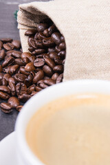 Coffee in white cup and roasted dark coffee beans in bag