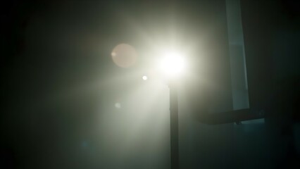 Bright light shining through foggy room, illuminating a dark metal railing, creating a dramatic atmosphere.