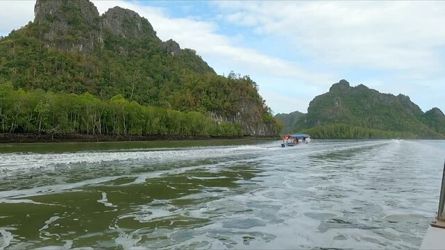 Langkawi Malaysia POV fast boat traveling along tropical river with other fast boats and river village