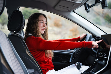 A woman driver using a GPS navigation system while driving her modern car. A caucasian girl...