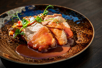 A succulent pork dish presented with a rich sauce and vibrant vegetables, garnished with fresh herbs, showcases culinary artistry at its finest in a cozy dining environment. 