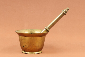 Antique brass mortar and pestle on a warm-toned background.