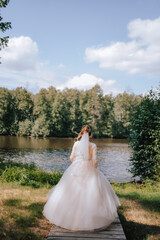A bride in a white dress walks along a wooden bridge to the water