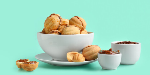 Bowl of sweet walnut shaped cookies with boiled condensed milk on turquoise background
