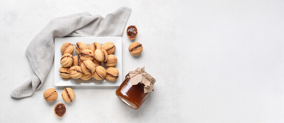 Plate with sweet walnut shaped cookies with boiled condensed milk on white background