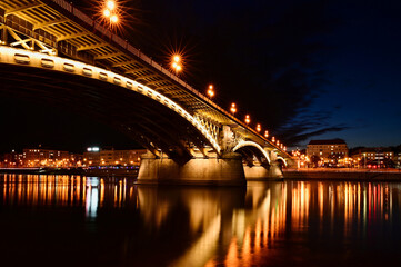 the Margaret bridge in Budapest. perspective view at bleu hour. illuminated steel arches. reflection on the water. tourism and travel concept. transportation and structural design. night photo