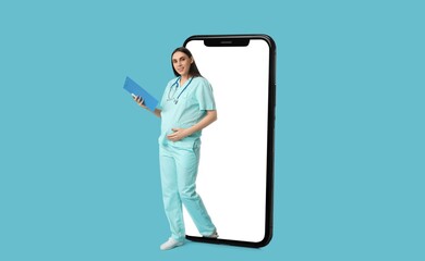 Young pregnant doctor with clipboard and big smartphone on light blue background