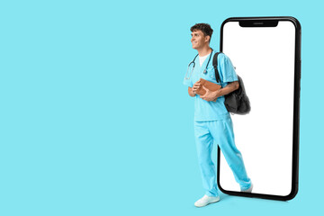 Male medical student with books and backpack on blue background