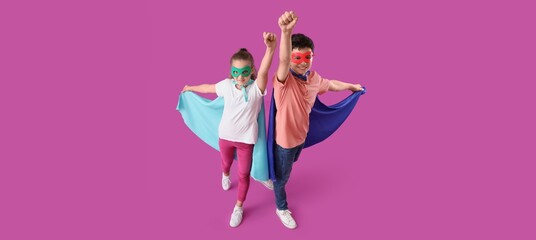 Little children in superhero costumes on purple background