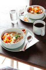 A healthy granola bowl with yogurt, mango, papaya, banana, honey, coconut flakes, and flax seeds. Served with a glass of water and a cup of coffee, creating a perfect balanced breakfast