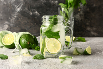 Mason jar of cold mojito, limes and mint on table