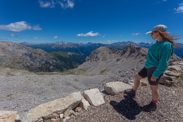 Girl looking at the awesome summer panorama in the Dolomites, Mount Latemar, Trentino, Italy. Travel in Dolomites. Tourism. Traveling photography and outdoor sport activity concept