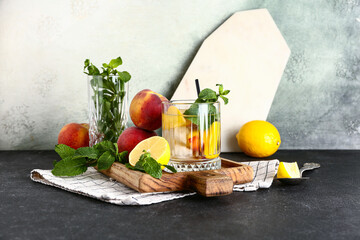 Glass of fresh peach lemonade with mint on black table