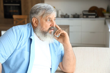 Afraid mature man at table in kitchen