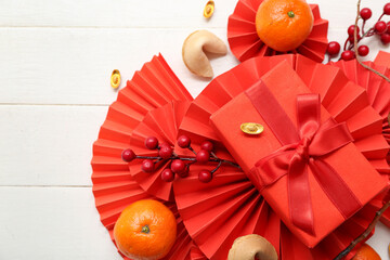 Gift box with fortune cookies, mandarins and Chinese symbols on white wooden background. New Year...