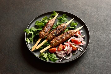 Lula kebab on wooden skewers served with fresh vegetables