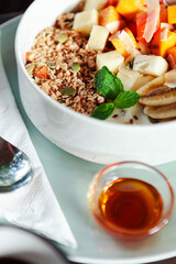 A healthy granola bowl with yogurt, mango, papaya, banana, honey, coconut flakes, and flax seeds. Served with a glass of water and a cup of coffee, creating a perfect balanced breakfast