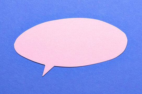 Pink cut out blank paper speech bubble of round shape with copy space for text on blue background, flat lay top view conceptual backdrop