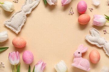 Frame made of tulips, Easter bunnies and eggs on beige background