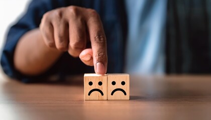 Man hand points on a wooden cube with happy smile face on bright side and unhappy face on dark side of wooden block cube for a positive mindset selection. Emotional state and mental health new