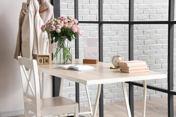 Calendar with date of International Women's Day and roses on table in room