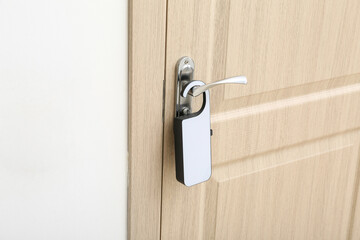 Light wooden door in hotel room with door hanger