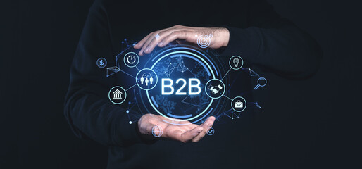 Futuristic B2B network concept with connected icons and hands framing a glowing digital interface on a dark background.