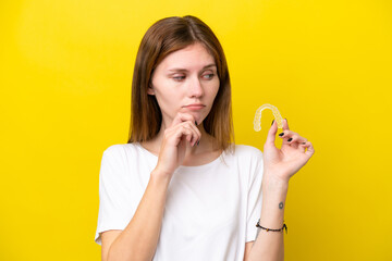 Young English woman holding invisible braces having doubts and thinking