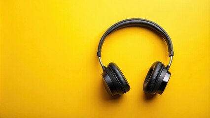 Naklejka premium Black headphones isolated on a vibrant yellow background, perfect for audio and music themed projects.