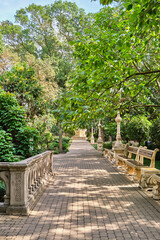 Elegant garden pathway with benches and lush greenery.