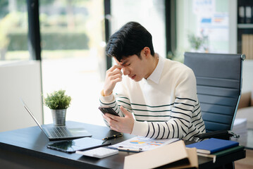 Frustrated young businessman working on a laptop computer sitting at his working place