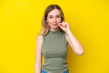 Blonde English young girl isolated on yellow background showing a sign of silence gesture