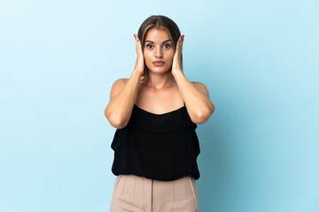Young Uruguayan woman isolated on blue background frustrated and covering ears