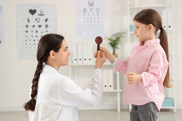 Female ophthalmologist with occluder and little girl in clinic