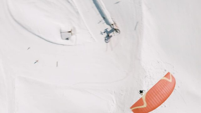 Un homme en parapente dans les montagnes enneig&eacute;es des alpes en suisse pendant l'hiver suivi par un drone FPV